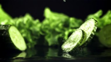 Taze salatalık parçaları masaya su damlatarak düşer. Film yavaş çekimde 1000 fp..