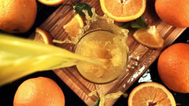 Sinaasappelsap met spetters wordt in het glas gegoten. Gefilmd is slow motion 1000 frames per seconde. — Stockvideo
