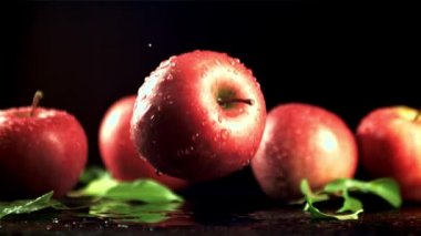 Taze kırmızı bir elma, üzerine su damlatılan bir masaya düşer. Film yavaş çekimde 1000 fp..