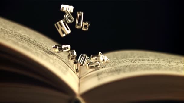 English letters fall on an open book. Filmed is slow motion 1000 frames per second. — Stock Video