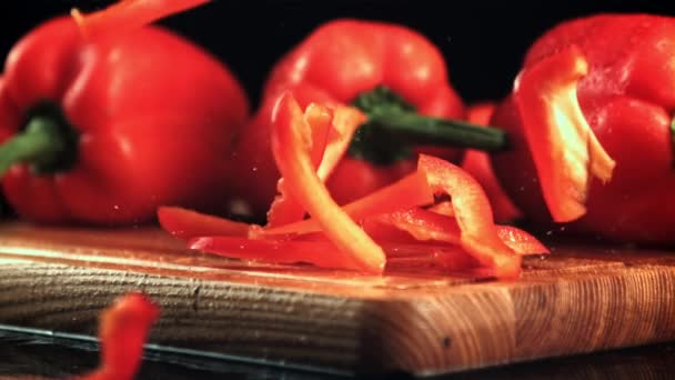Pieces of red sweet pepper fall on a wooden cutting board. Filmed is slow motion 1000 fps. — Stockvideo