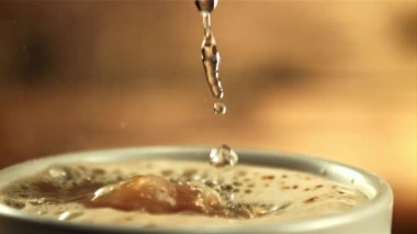 Sıcak su bir kahve bardağına dökülür. Saniyede 1000 kare yavaş çekimde çekiliyor..