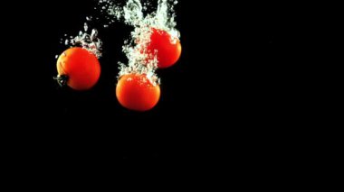 Taze domatesler hava kabarcıklarıyla suya düşer. Saniyede 1000 kare yavaş çekimde çekiliyor..