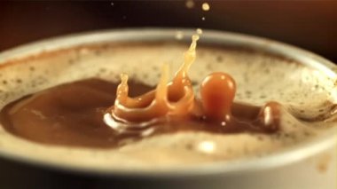 Damlalar bir fincan sütlü kahveye düşer. Saniyede 1000 kare yavaş çekimde çekiliyor..