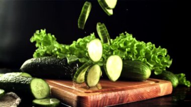 Taze salatalık parçaları kesme tahtasına düştü. Film yavaş çekimde 1000 fp.