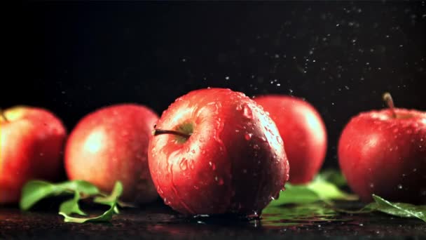 Water with splashes falls on the red apple. — стоковое видео