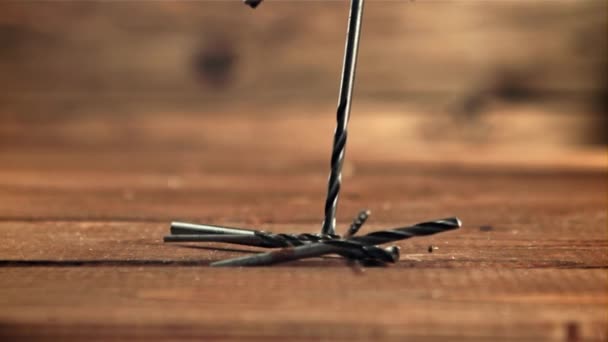 Drill bits fall on the wooden table. Filmed is slow motion 1000 fps. — Wideo stockowe