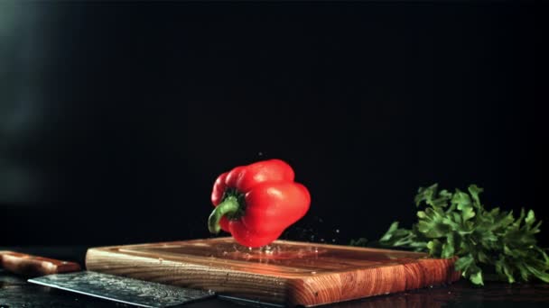 Γλυκές πιπεριές πέφτουν σε ένα ξύλινο ξύλο κοπής. Ταινία είναι αργή κίνηση 1000 fps. — Αρχείο Βίντεο