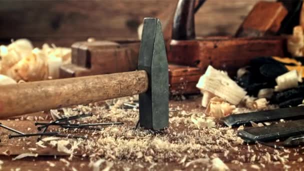 A hammer falls on a table with sawdust and nails. Filmed is slow motion 1000 frames per second. — Vídeos de Stock