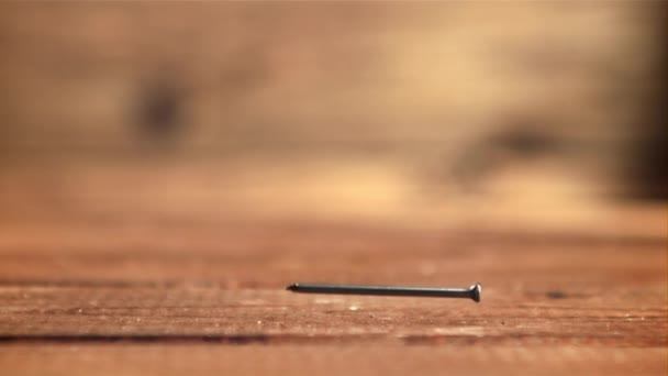 One nail falls on a wooden table. Filmed is slow motion 1000 frames per second. — Stockvideo