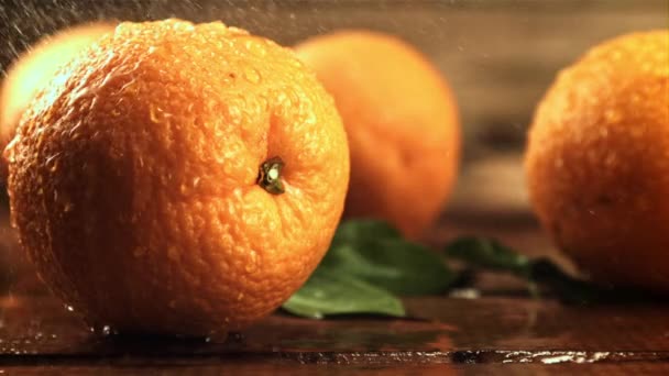 Gotas de agua con salpicaduras caen sobre naranjas frescas. Filmado en cámara lenta 1000 fotogramas por segundo. — Vídeo de stock