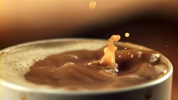 Damlalar bir fincan sütlü kahveye düşer. Saniyede 1000 kare yavaş çekimde çekiliyor.. — Stok video