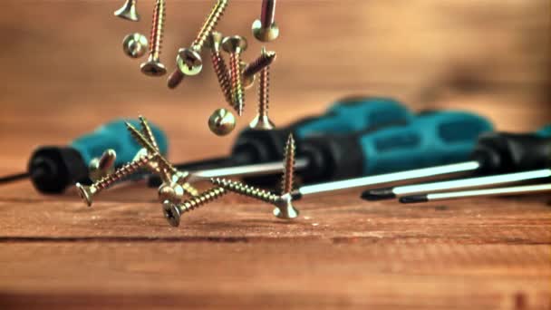 Los tornillos autorroscantes caen sobre una mesa de madera. Filmado en cámara lenta 1000 fotogramas por segundo. — Vídeo de stock