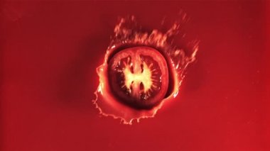 Yuvarlak bir domates parçası su damlatarak domates suyuna düşer. 1000 fps hızla yüksek hızlı bir kamerayla çekildi..