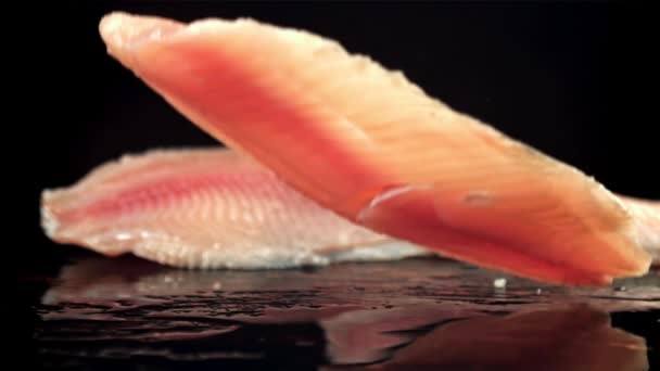 Filety rybne spadają na mokry stół z rozpryskami. Nagrywane na szybkiej kamerze z prędkością 1000 fps. — Wideo stockowe