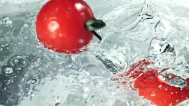 Domatesler su sıçratarak berrak suya düşer. Film yavaş çekimde çekilmiştir. 1000 fp..