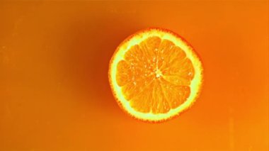 Yuvarlak bir portakal parçası portakal suyuna su sıçramasıyla düşer. 1000 fps hızla yüksek hızlı bir kamerayla çekildi..