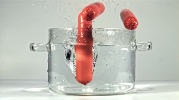 Würstchen fallen in einen klaren Topf mit Spritzern. Gefilmt mit einer Hochgeschwindigkeitskamera bei 1000 fps. — Stockvideo