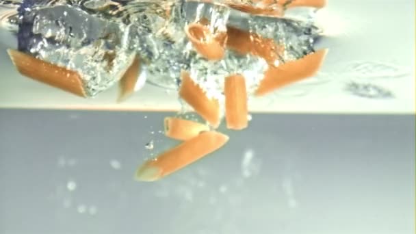 De penne pasta valt onder water met luchtbelletjes. Gefilmd op een hoge snelheidscamera met 1000 fps. — Stockvideo