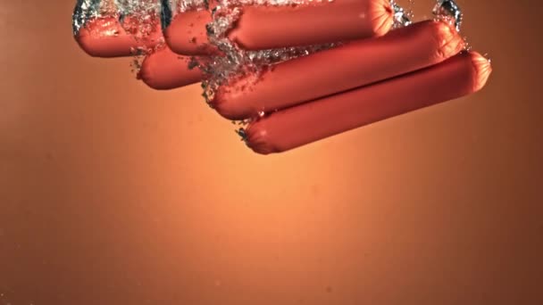 Las salchichas caen bajo el agua con burbujas de aire. Filmado en una cámara de alta velocidad a 1000 fps. — Vídeo de stock