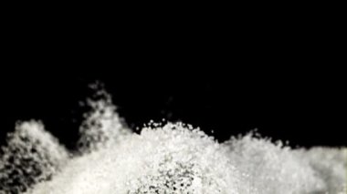 Şeker yükselir ve uçarken dağılır. Siyah bir arka planda. Film yavaş çekimde 1000 fp..