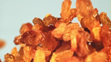 Kuru üzümler yukarı çıkar ve düşer. Mavi arka planda. Film yavaş çekimde 1000 fp..