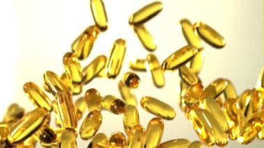 Omega 3 vitamin kapsülleri yükselir ve düşer. Gri bir arka planda. Film yavaş çekimde 1000 fp..