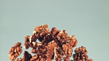 Soyulmuş cevizler yükselir ve düşer. Mavi arka planda. Film yavaş çekimde 1000 fp..