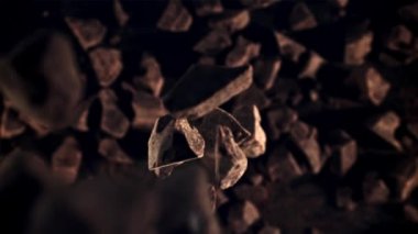 Çikolata parçaları düşüyor. Üst Manzara. Karanlık bir arka plana karşı. 1000 fps hızla yüksek hızlı bir kamerayla çekildi..