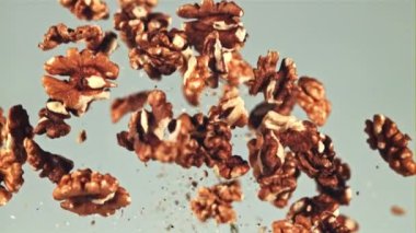 Soyulmuş cevizler yükselir ve düşer. Mavi arka planda. Film yavaş çekimde 1000 fp..