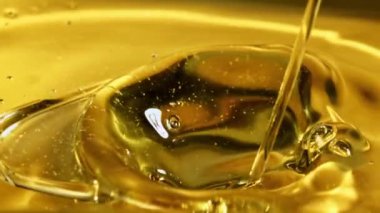 Bir zeytin yağı püskürtüsü dalgalar ve sıçramalarla akar. Makro arka plan. 1000 fps hızla yüksek hızlı bir kamerayla çekildi.. 