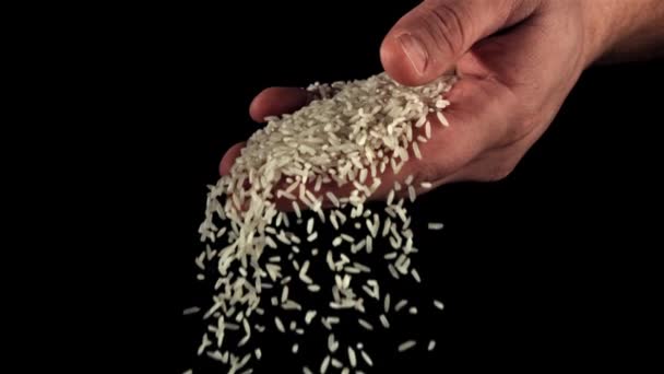 Een Handvol Ongekookte Rijst Valt Van Een Mensenhand Een Zwarte — Stockvideo