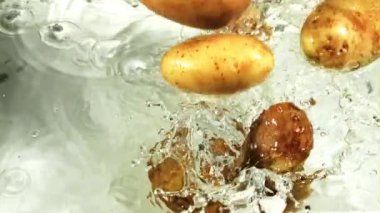 Patatesler su ve hava kabarcıklarıyla suya düşer. Makro arka plan. 1000 fps 'de yüksek hızlı bir kamerayla çekildi. Yüksek kaliteli FullHD görüntüler