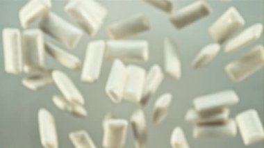 Bir grup diş eti uçar ve uçarken döner. Gri bir arka planda. Film yavaş çekimde 1000 fp..