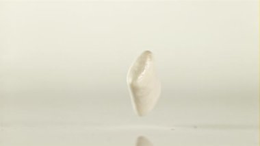 Sakız masaya düşer ve uçarken yavaşça döner. Beyaz bir arka planda. Film yavaş çekimde 1000 fp..