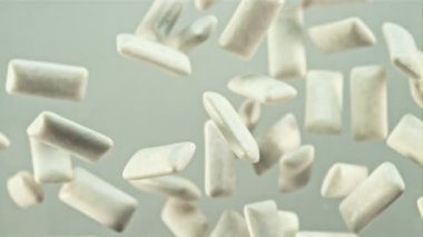 Sakız uçuşta yavaşça döner. Gri bir arka planda. Film yavaş çekimde 1000 fp..