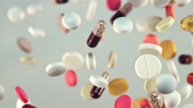 Uçuşta bir sürü farklı hap uçar ve döner. Beyaz bir arka planda. Film yavaş çekimde 1000 fp..