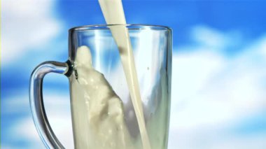 Kupanın içine bir süt akıntısı dökülüyor. Mavi gökyüzüne karşı. Film yavaş çekimde 1000 fp..