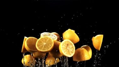 Taze limonların yarısı su damlalarıyla uçar ve havada döner. Siyah bir arka planda. 1000 fps hızla yüksek hızlı bir kamerayla çekildi..