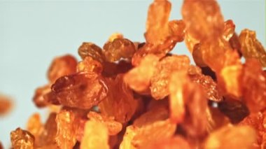 Kuru üzümler yukarı çıkar ve düşer. Mavi arka planda. Film yavaş çekimde 1000 fp..