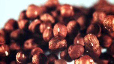 Soyulmuş fındıklar yükselir ve uçuşta döner. Mavi arka planda. Film yavaş çekimde 1000 fp..