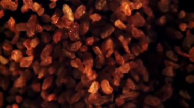 Kuru üzümler yukarı çıkar ve düşer. Siyah bir arka planda. Üst Manzara. 1000 fps hızla yüksek hızlı bir kamerayla çekildi..