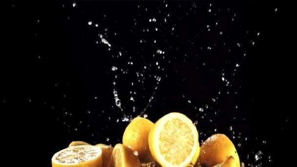 レモンの半分が飛び立ち 水の飛沫で落下します 黒を背景に 1000 Fpsで高速カメラで撮影 — ストック動画
