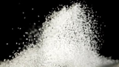 Şeker yükselir ve uçarken dağılır. Siyah bir arka planda. Film yavaş çekimde 1000 fp..