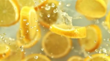 Taze limon parçaları bir damla suyla uçarken yavaşça döner. Beyaz bir arka planda. 1000 fps hızla yüksek hızlı bir kamerayla çekildi..