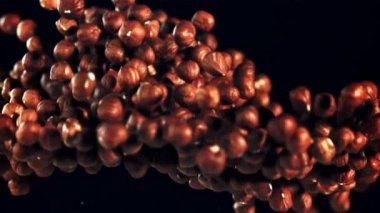 Soyulmuş fındık yığını yukarı doğru yükselir. Siyah bir arka planda. 1000 fps hızla yüksek hızlı bir kamerayla çekildi..