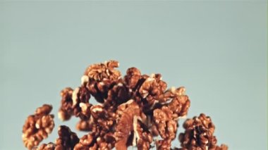 Soyulmuş cevizler yükselir ve düşer. Mavi arka planda. Film yavaş çekimde 1000 fp..