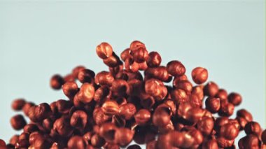 Soyulmuş fındıklar uçar ve düşer. Mavi arka planda. Film yavaş çekimde 1000 fp..