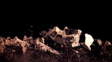 Bir yığın çikolata parçası yükselir ve düşer. Siyah bir arka planda. Film yavaş çekimde 1000 fp..