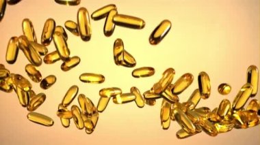 Bir sürü Omega 3 vitamini yukarı aşağı gidiyor. Turuncu arka planda. Film yavaş çekimde 1000 fp..